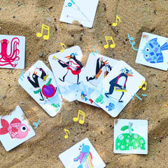Bunte Spielkarten mit musizierenden Tieren auf Sand, ideal für kinderfreundliches Lernen und Spielen