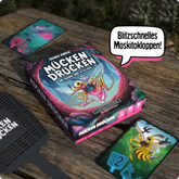 Mücken Drücken Spielbox mit bunten Karten und Moskitokloppen auf Holztisch