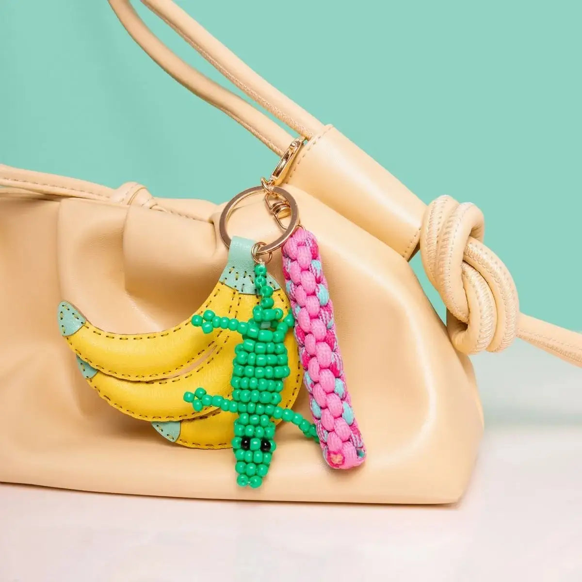 Bunte Schlüsselanhänger mit Banane, Krokodil und geflochtenem Band an cremefarbener Tasche